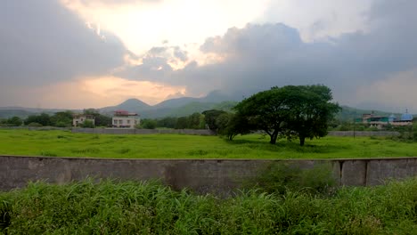 Panoramic-view-of-a-small-village-with-beautiful-scenic-sunset-view-in-monsoon-season-with-stormy-clouds-in-Maharashtra,-India-|-Aerial-view-of-scenic-sunset-background-of-mountains-and-monsoon-clouds