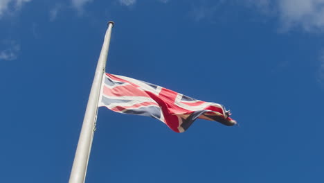 Union-Flag-In-Half-Mast-Against-Blue-Sky