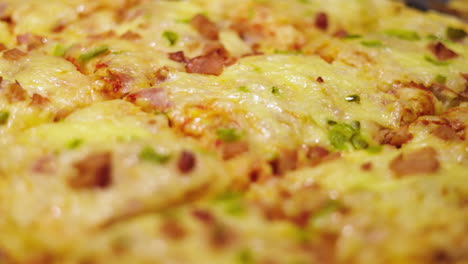 Closeup-of-sliced-ham-and-veggie-square-pizza,-slow-motion-panning-out