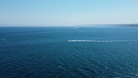 Lonely-boat-speeding-through-blue-tropical-sea-water,-aerial-view