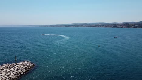 Boat-speeding-in-majestic-blue-water-near-Spanish-coastline,-aerial-view