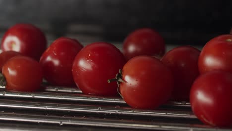 Ripe-red-tomatoes,-freshly-washed-falling-on-metal-drier-in-close-up