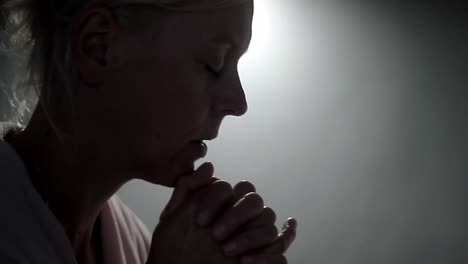 Woman-praying-to-god-with-hands-together-on-grey-background-stock-footage