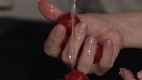 Washing-tomatoes-under-the-tap,-closeup-on-hands