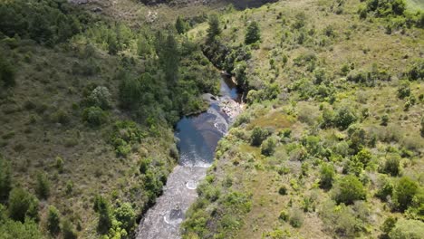 Cascading-river-over-a-valley,-aerial-view