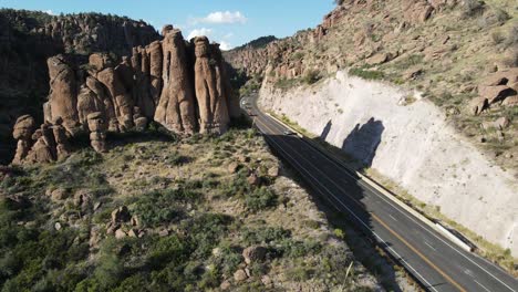 Aerial-Ascending-Reveal-shot-of-highway-surrounded-by-giant-boulders