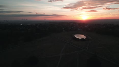 Luftaufnahme-Bewegt-Sich-Vorwärts-über-Wimbledon-Common-Bei-Sonnenaufgang-Mit-Der-Skyline-Von-London-Im-Hintergrund