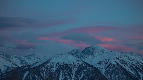 Wolken-Rollen-über-Die-Schneebedeckten-Berge,-Während-Ein-Farbenfroher-Sonnenuntergang-In-Die-Abenddämmerung-übergeht---Zeitraffer