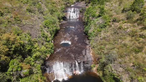 People-cooling-off-at-the-waterfall,-drone-view