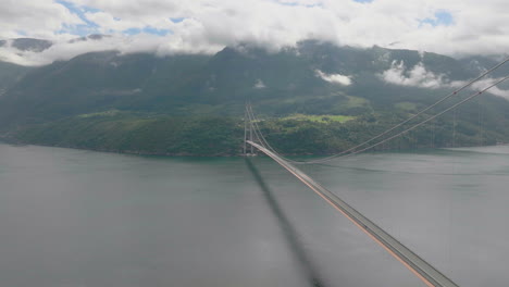 Epic-aerial-next-to-Hardanger-suspension-bridge-over-fiord,-scenic-landscape