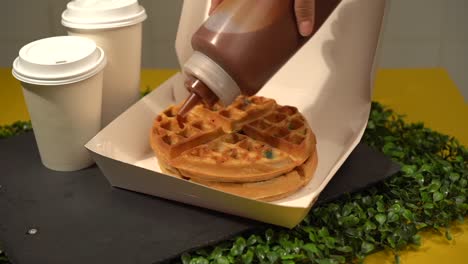 Adding-topping-milk-caramel-sweet-candy-to-waffles-in-slow-motion