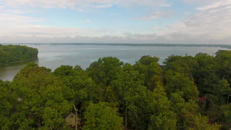 Drone-shot-of-Indian-Lake-in-Ohio,-rising-aerial-shot-from-trees-revealing-the-water