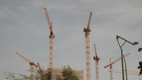 Many-yellow-Tower-Cranes-against-blue-sky-on-construction-site