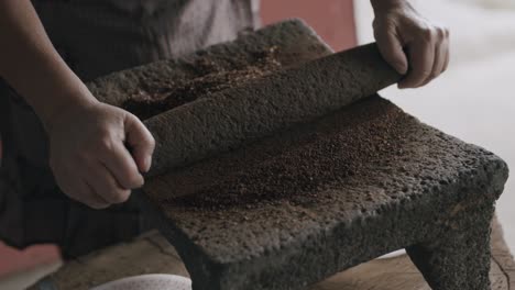 Slow-motion-footage-of-person-slowly-grinding-coffee-beans-into-a-fine-ground-on-a-volcanic-stone