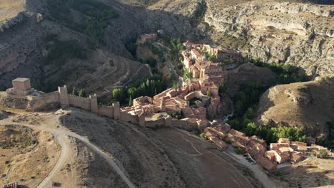 Backward-aerial-view-of-medieval-village-of-Albarracin,-Teruel,-Spain,-in-a-late-summer-morning