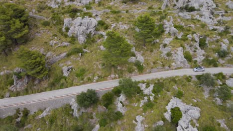 Long-sideways-panning-shot-following-car-peugeot-208-down-winding-road-at-Sa-Calobra,-Mallorca,-Spain