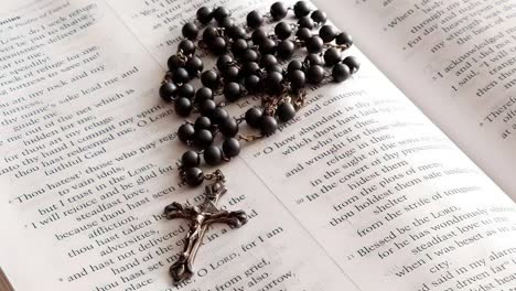 Rosary-beads-placed-on-open-bible-close-up-panning-shot