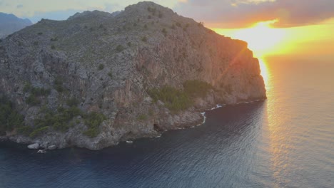 Downwards-drone-shot-of-mountain-with-sunset-on-the-background-above-the-Mediterranean-sea-at-Sa-Calobra,-Mallorca,-Spain