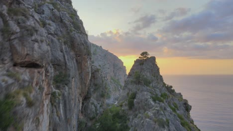 Flying-closely-over-mountain-peaks-revealing-a-sunset-and-Mediterranean-sea-at-Sa-Calobra,-Mallorca,-Spain