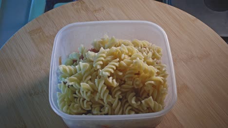 Adding-Cooked-Fusilli-Pasta-Into-Spicy-Chicken-With-Beans-In-Plastic-Food-Container
