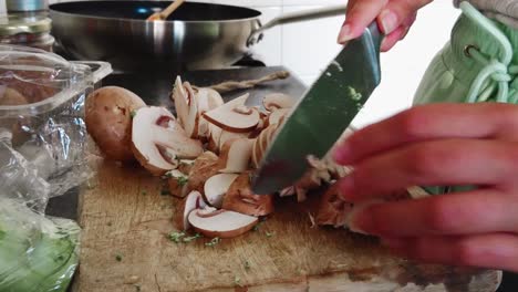 woman-in-home-kitchen-cutting-champignon-mushrooms-on-wooden-cutting-board