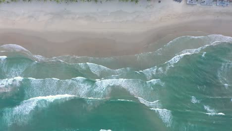 Ocean-waves-crashing-into-white-sand-beach-filmed-from-above-by-drone