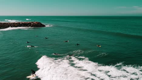 Aerial-Shot-Of-Group-Of-Surfers-Riding-Wave-Together,-Ericeira,-Portugal