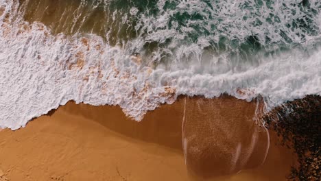 Overhead-Shot-Of-Beautiful-Wave-Crashing-On-Magical-Sandy-Beach,-Ericeira,-Portugal