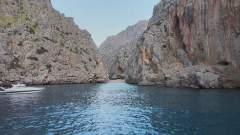 Long-drone-shot-starting-low-above-the-mediterranean-sea-rising-over-the-beach-of-torrent-de-pareis-and-entering-the-canyon-of-Sa-Calobra,-Mallorca,-Spain