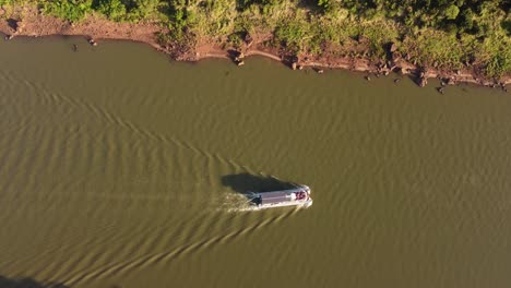 Aerial-tracking-shot-of-tourist-boat-cruising-on-Iguazu-River-during-sunny-day-between-Argentina-and-Brazil-Country
