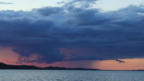 Static-shot-a-rain-and-thunderstorm-at-sunset-moving-above-a-lake