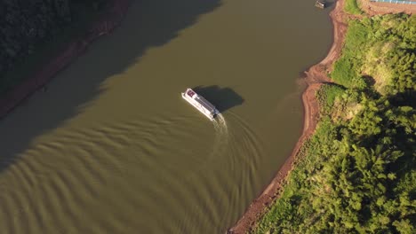 Tourist-boat-turning-back-on-Iguazu-river-at-sunset,-border-between-Argentina-and-Brazil