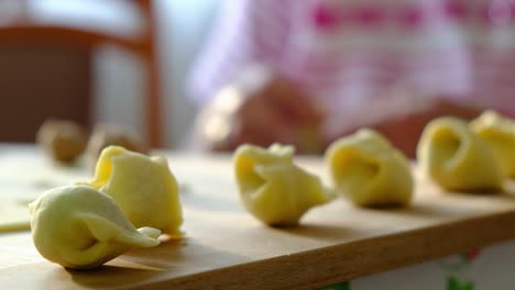 Preparation-of-popular-food-dish,-Polish-'Little-Ears'-Uszka-Dumplings-and-Pierogi---Polish-Cuisine--Grandmother-old-hands-working-dough---daughter-helps---Working-in-the-kitchen