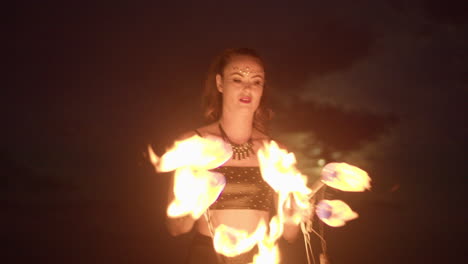 Woman-Igniting-Second-Fire-Fan-Against-Cloud-Covered-Moon,-Medium-Shot-Slowmo