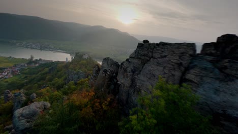 Adventurous-descending-FPV-shot-capturing-mighty-stone-formations,-Dürnstein,-and-its-historic-ruin-surrounded-by-nature