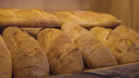 Bakery-shop-shelf-filled-with-freshly-baked-golden-buns,-bread-background
