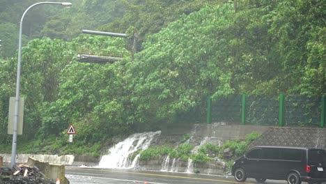 Slow-motion-capturing-cars-driving-in-dangerous-condition-with-bad-visibility,-heavy-rainfall-with-overflowing-of-water-on-the-roadside-at-Hsuehshan-Tunnel-at-Hualien-City,-Taiwan,-storm-and-typhoon