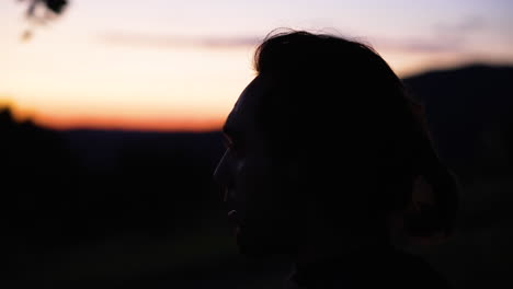 Close-up-of-a-head-of-a-young-man-in-front-of-mountains-and-a-beautiful-orange-sundown