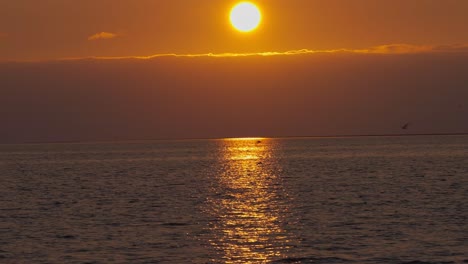 Dramatic,-beautiful,-epic-red-and-orange-sunset-in-the-ocean,-wide-shot-tilt-up