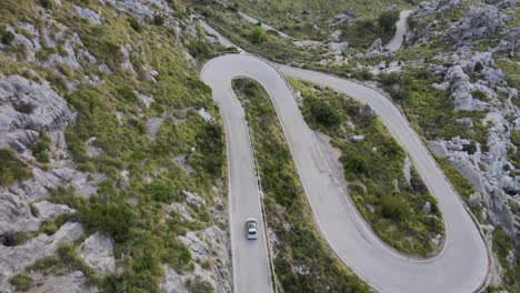 Following-car-on-a-winding-mountain-road-with-hairpin-bends-on-a-sunny-day-at-Sa-Calobra,-Mallorca,-Spain