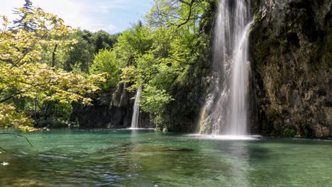 Ein-Wunderschöner-Wasserfall-Fällt-Auf-Einen-Grünen-See,-Statische-Weitwinkelaufnahme