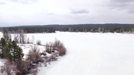 Drone-Aerial-of-the-winter-showing-the-vacation-homes-around-Island-Park-Reservoir-in-Island-Park-Idaho-cabins-on-the-side-of-the-lake