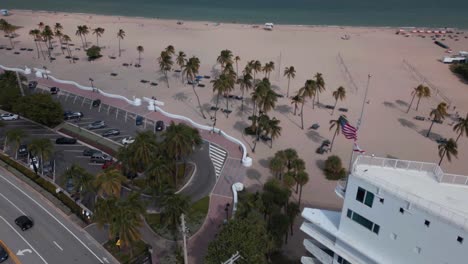 Aerial-View-of-a-sandy-beach-with-a-palm-trees-in-Fort-Lauderdale-Florida,-slider-wide-shot