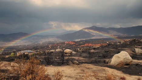 Panning-view-of-burned-valley-with-rain-and-rainbow-in-the-sky