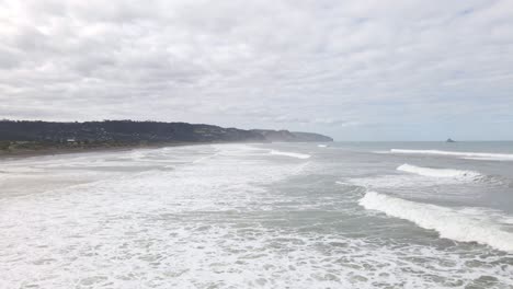 Slow-motion-dolly-shot-of-waves-crashing-onto-Muriwai-Beach,-New-Zealand
