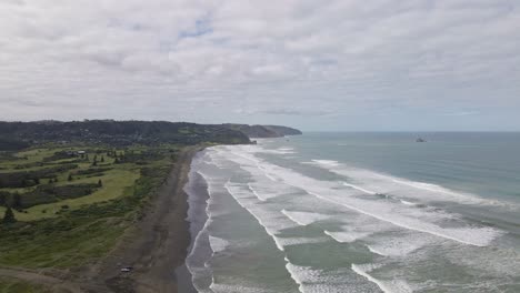 Toma-Aérea-Descendente-Sobre-La-Impresionante-Playa-De-Arena-Negra-De-Muriwai,-Nueva-Zelanda