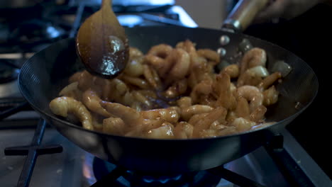 Frozen-Spicy-Prawns-Being-Cooked,-Heated-And-Stirred-And-Wok-In-Kitchen