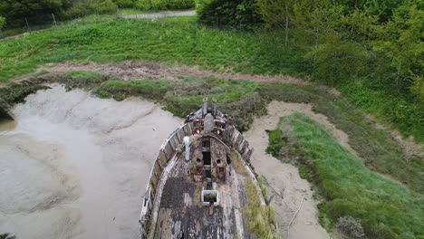 Aerial-view-of-a-abandoned-boat-stuck-in-mud-at-Wat-Tyler-Country-Park,-Basildon,-UK---reverse,-tilt,-drone-c