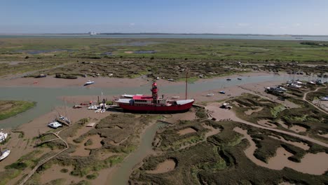 Aerial-view-away-from-a-stranded-LV15-Trinity-Lightvessel,-sunny-Tollesbury,-UK---pull-back,-drone-shot