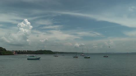 Timelapse-static-shot-of-a-beautiful-lake-with-calm-waters-many-single-floating-boats-and-a-view-of-the-big-clouds-in-the-sky-on-a-summer-day